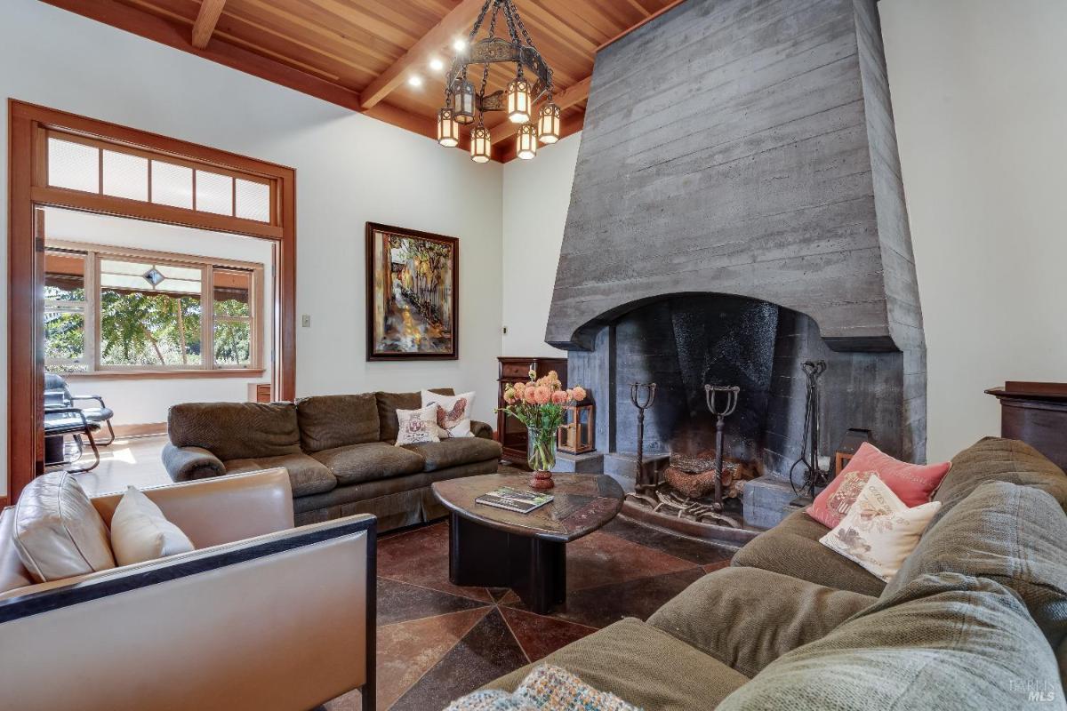 Living room with a large fireplace, sofas, and wooden ceiling beams.