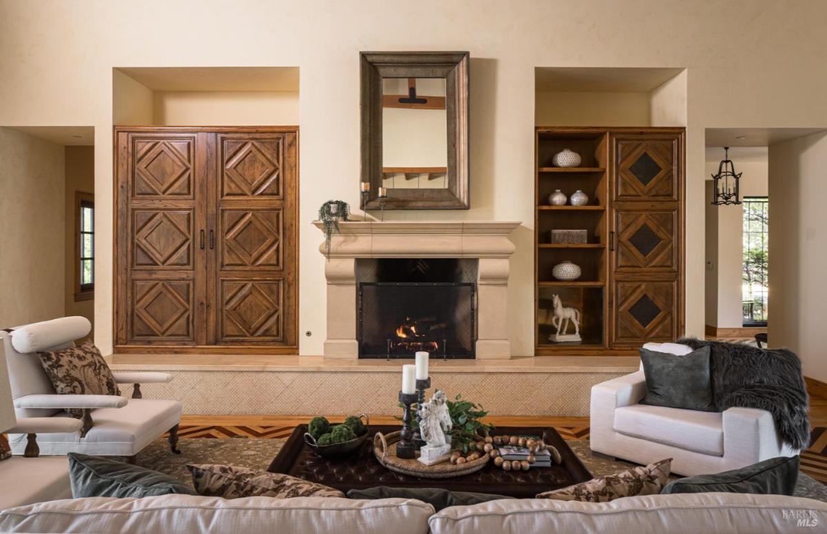 Living room with a fireplace, wood-paneled cabinets, and armchairs.