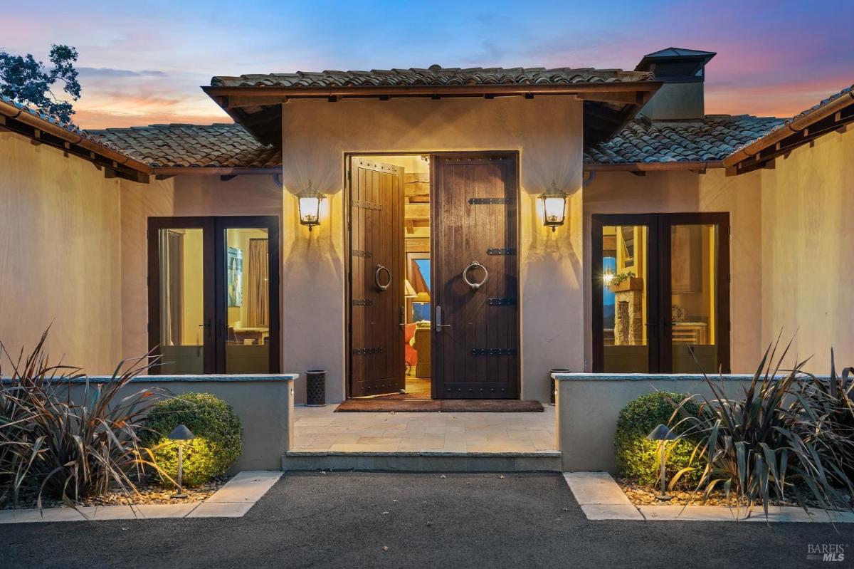 Front entry with large wooden double doors, flanked by lantern lights.