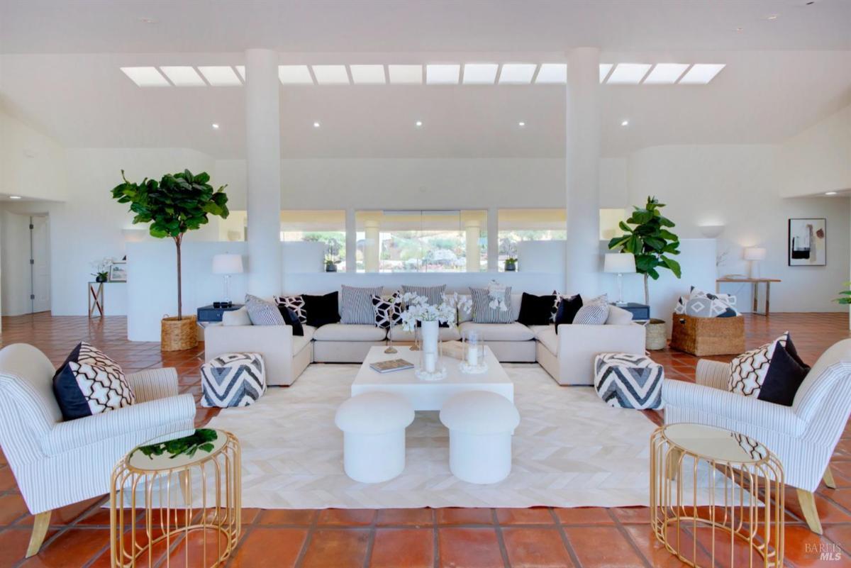 A living room with a large sectional sofa, white walls, and natural light.