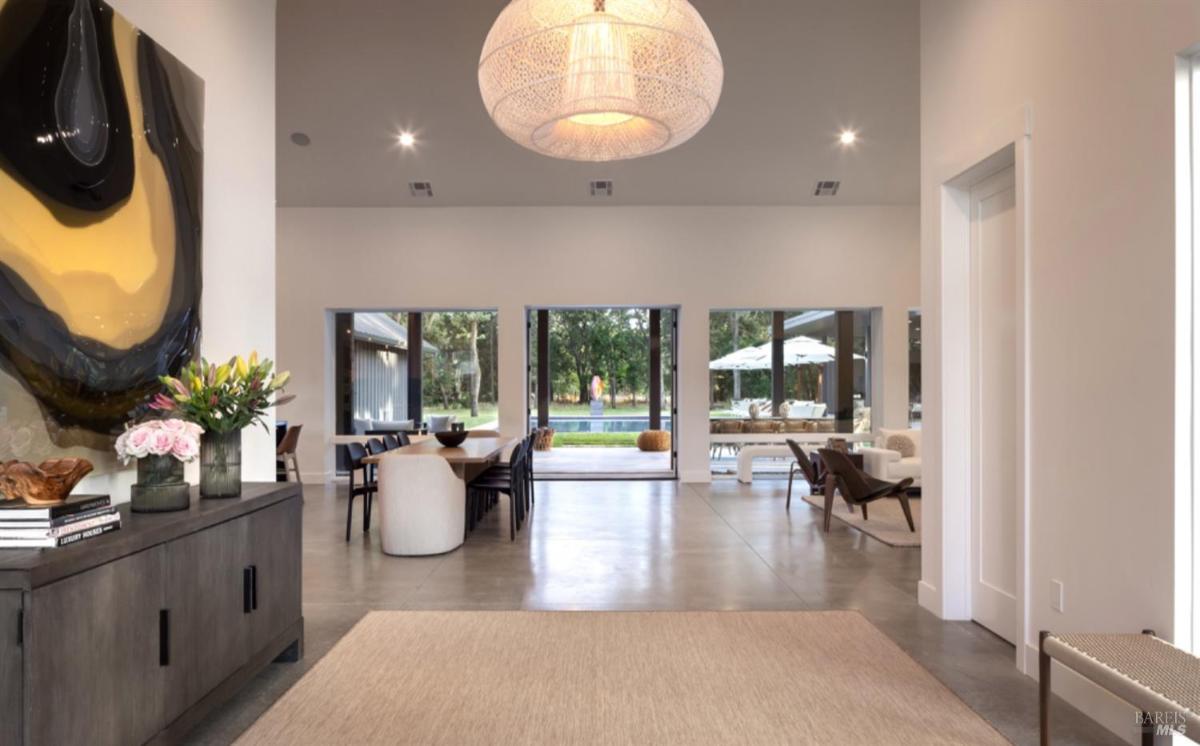 A foyer with a clear view leading to the dining area, living space, and pool through large sliding glass doors.