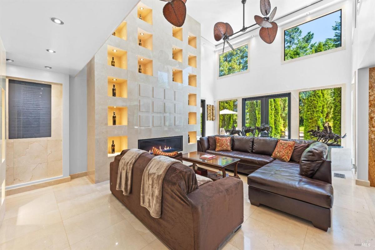 A living room with a modern design, featuring a fireplace and large windows.