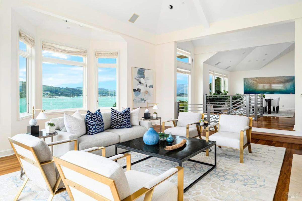 Living room with large windows and seating, overlooking water views.