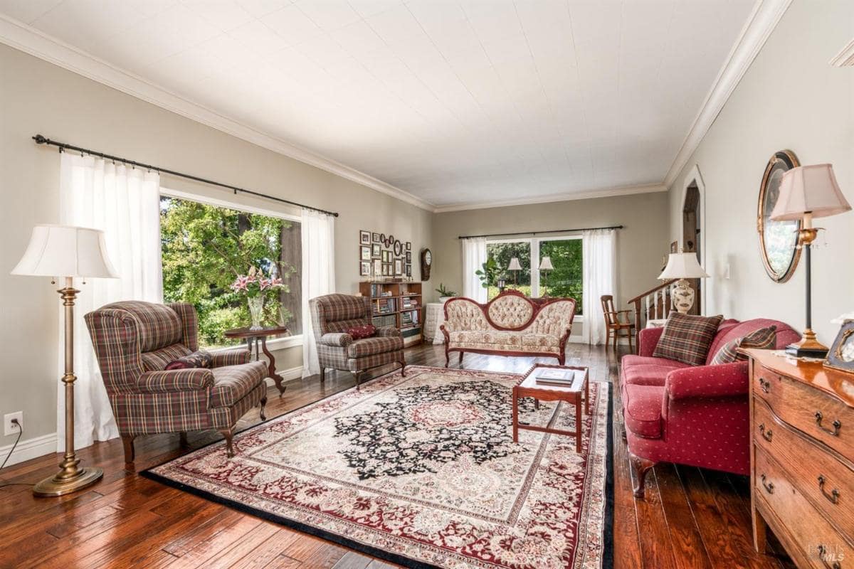 Living room with armchairs, a sofa, and large windows.