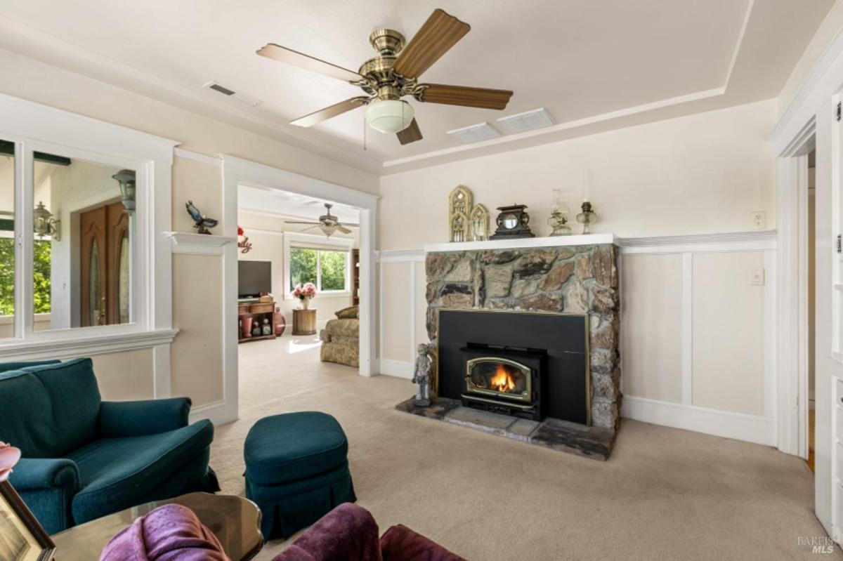 Living room with a stone fireplace and ceiling fan.