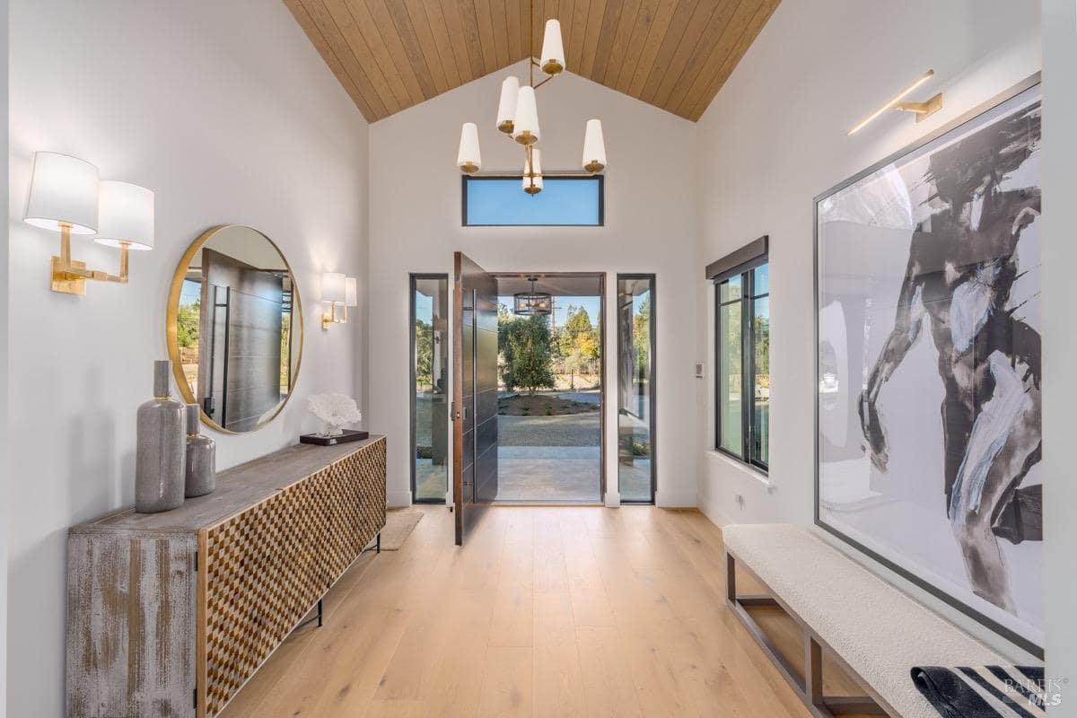 Modern entryway with vaulted wood ceiling, glass door, and stylish decor.