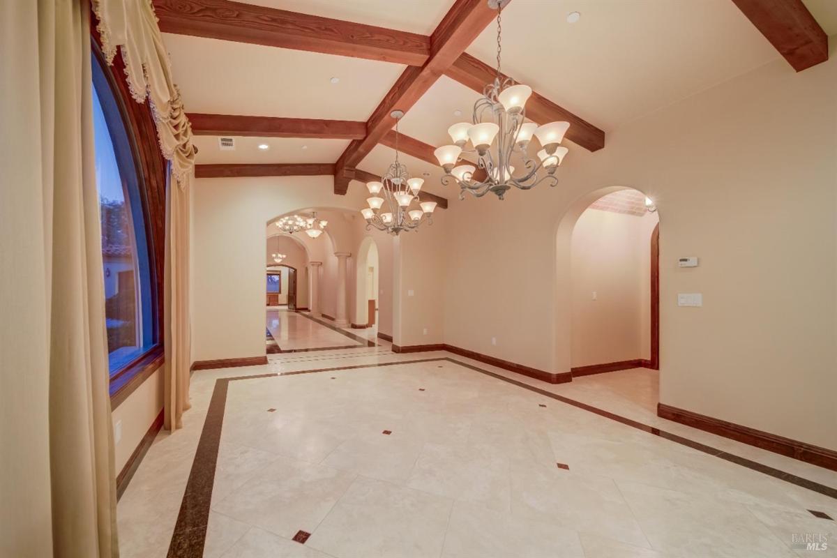 A spacious hallway with chandeliers and arched doorways. 