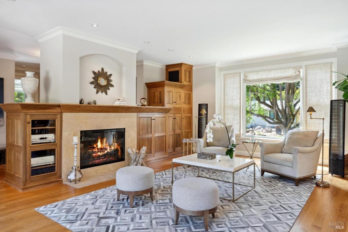 Living room with a fireplace, built-in cabinetry, and armchairs.