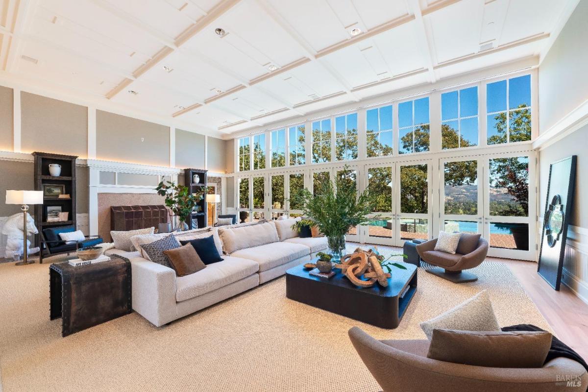 Living room with large sofas, a coffee table, and floor-to-ceiling windows.