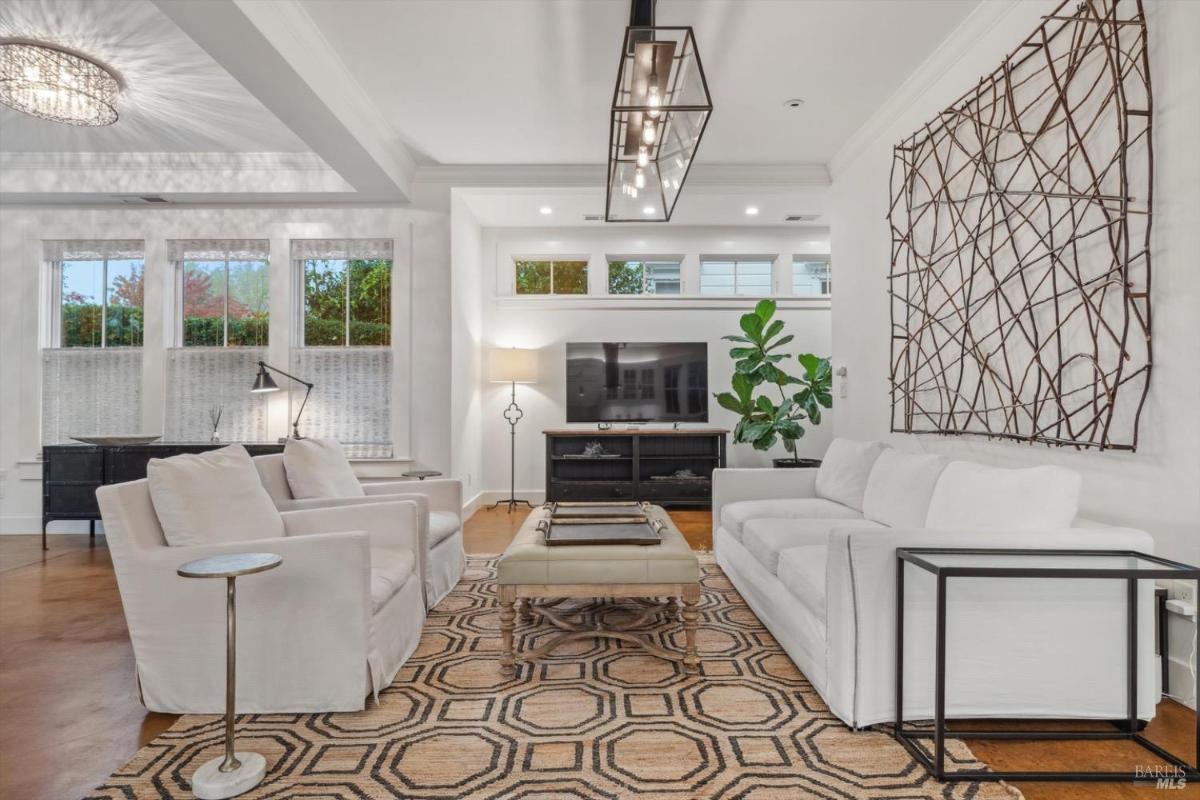 Living room with white furniture, a TV, and a geometric-patterned rug.