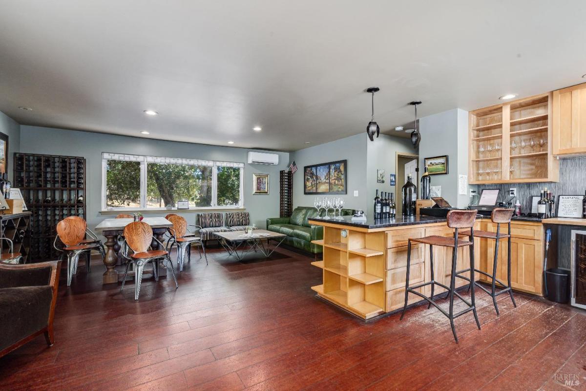 Room with a bar area, seating, and large windows overlooking trees.