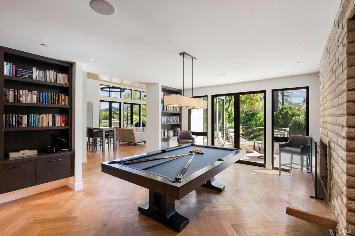 Game room featuring a billiards table, built-in bookshelves, and sliding glass doors leading to an outdoor space.