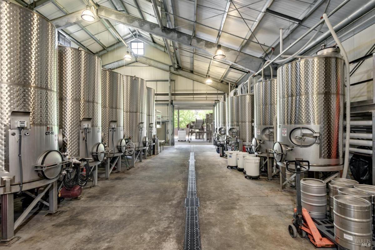 Winery facility with large stainless steel fermentation tanks and open space.