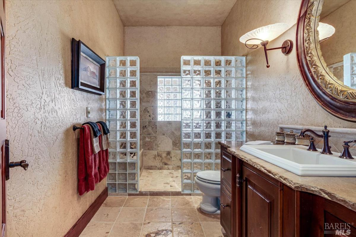 A bathroom with shower area enclosed with frosted glass.