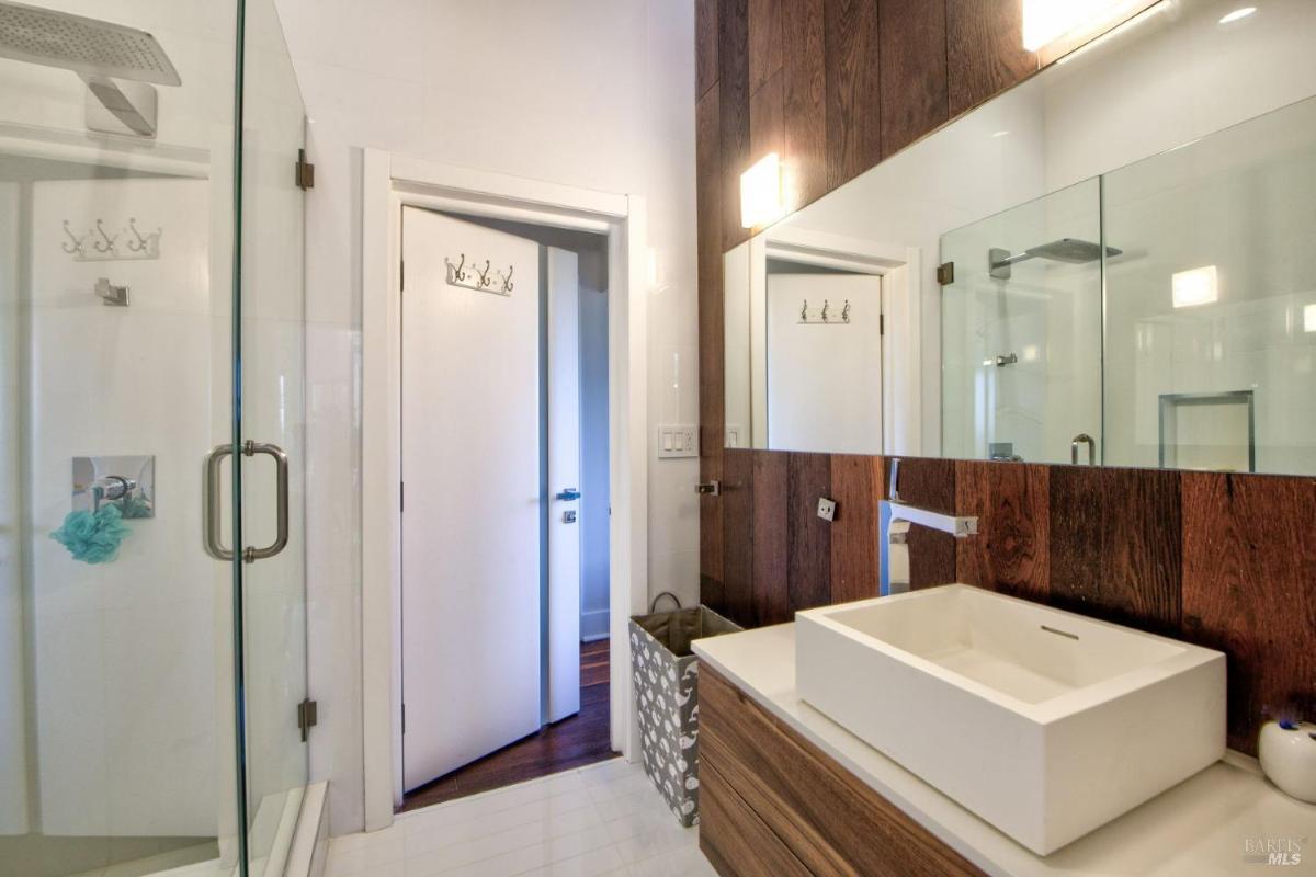 A bathroom with a glass shower enclosure and a single sink.