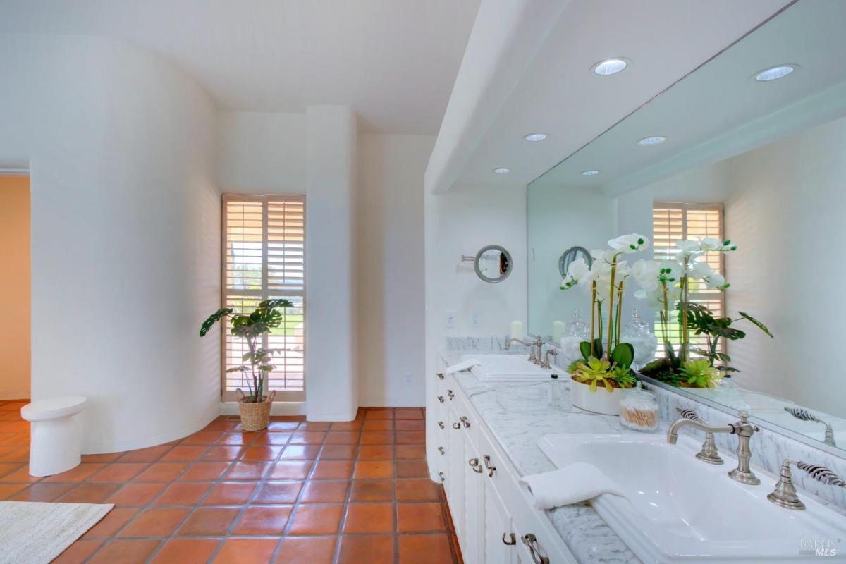 A bathroom with double sinks, marble countertop, and a large mirror.