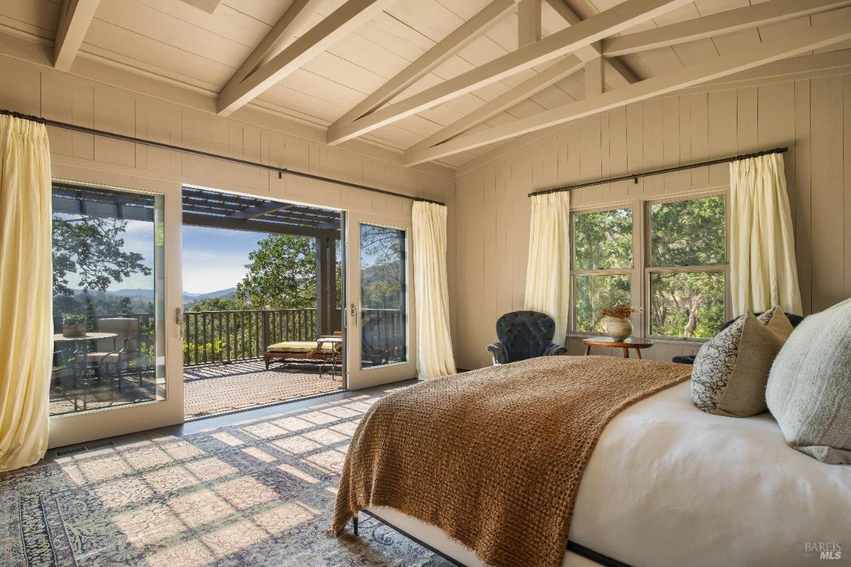 Bedroom with a bed, armchairs, and a window overlooking the outdoors.