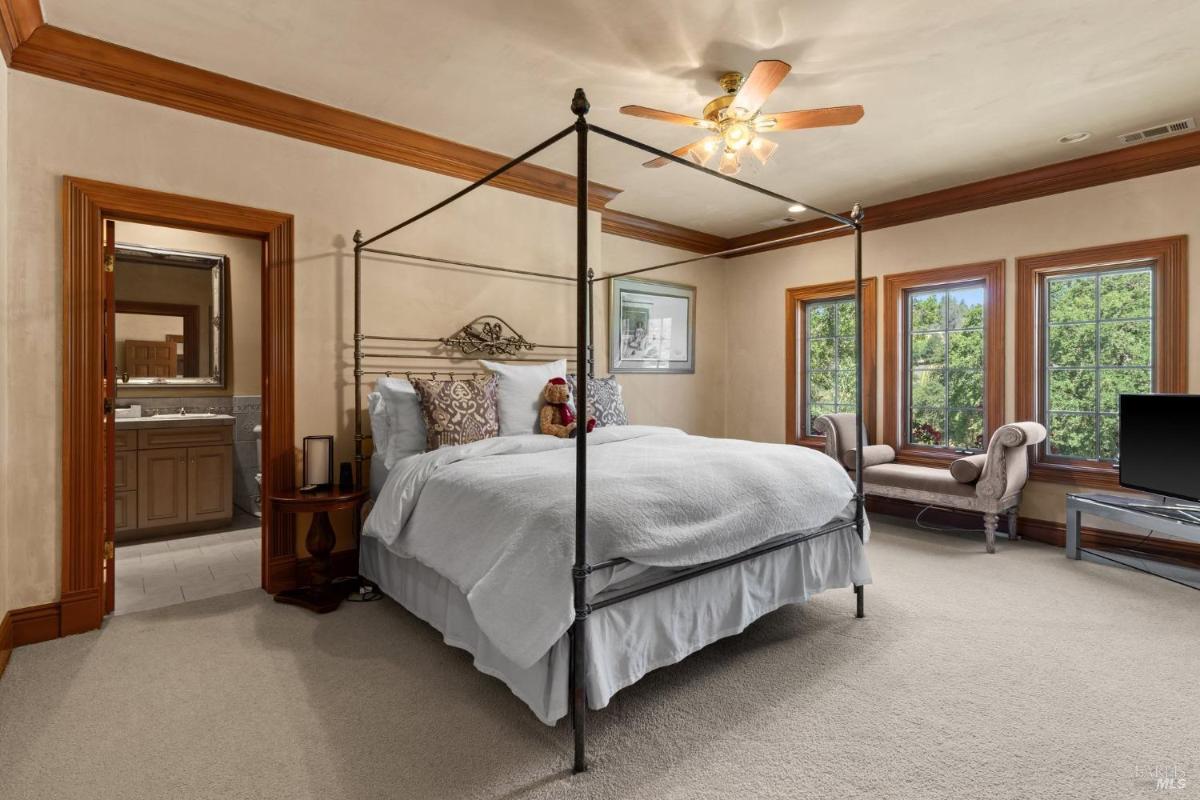 Bedroom with canopy bed, seating nook, and adjoining en-suite bathroom with serene outdoor views.