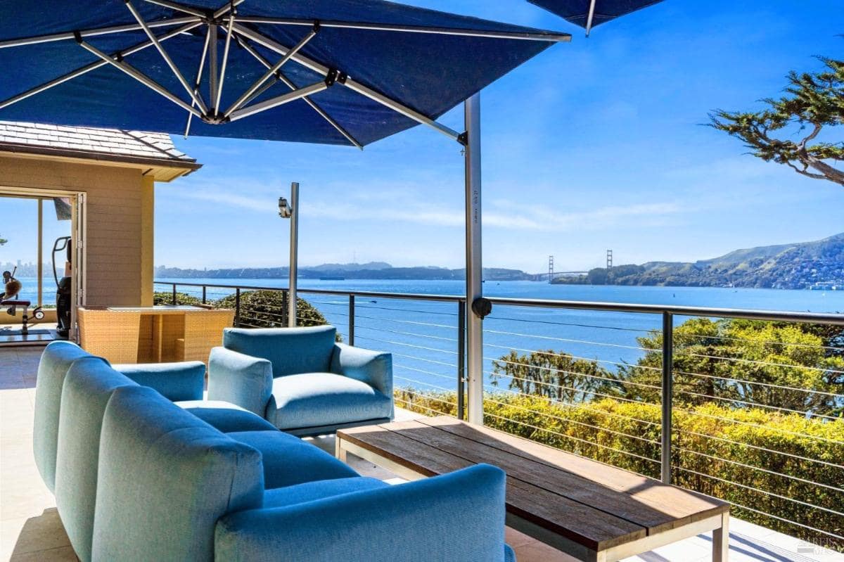 A spacious terrace with comfortable seating, shaded by a large umbrella, and views of the Golden Gate Bridge.