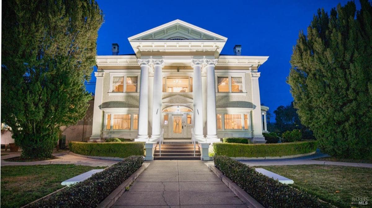 Front view of a house with illuminated pillars at night.