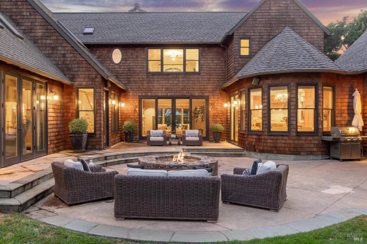 Outdoor patio with wicker seating, fire pit, and a house exterior.