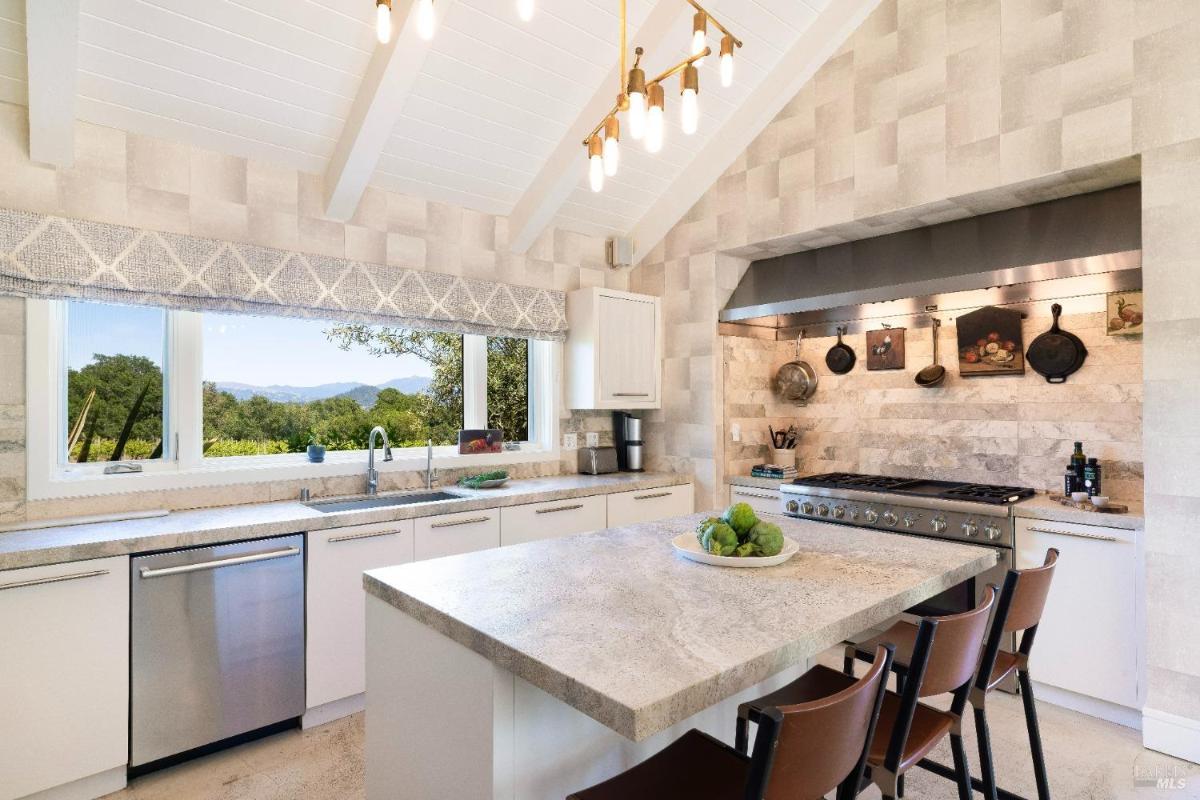 Kitchen with stone countertops, large windows, and a gas stove.