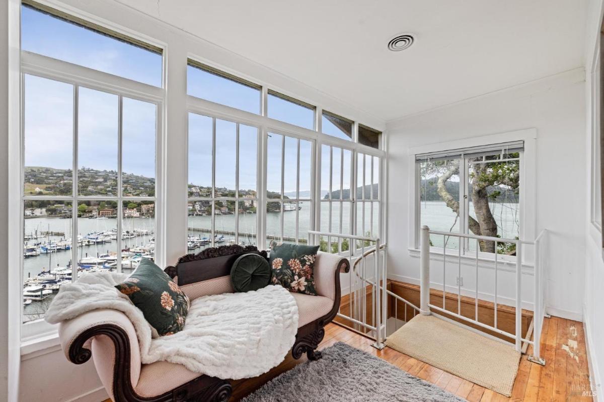 Sitting area with a couch and large windows overlooking a marina.