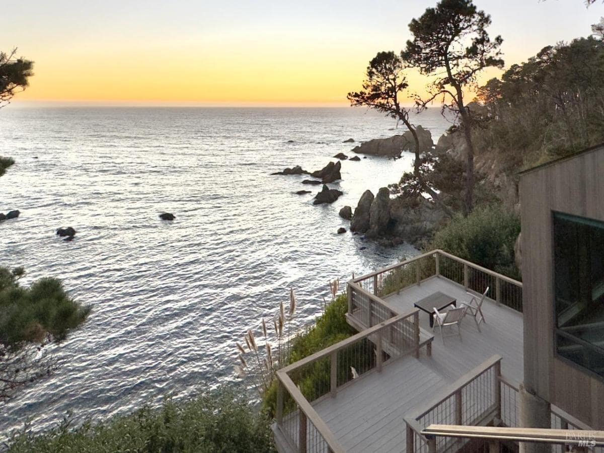 A deck overlooking the ocean with railings and chairs facing the water.