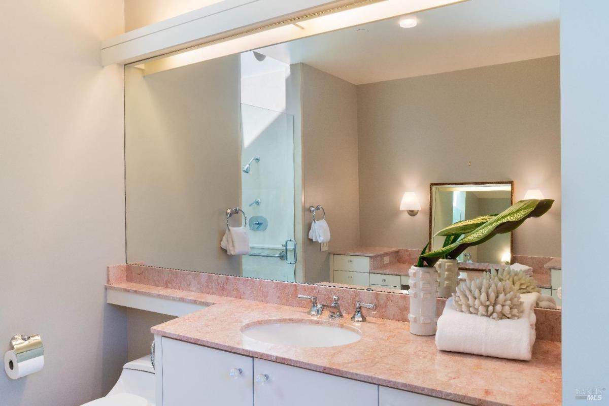 A bathroom vanity with a pink marble countertop and a large mirror.