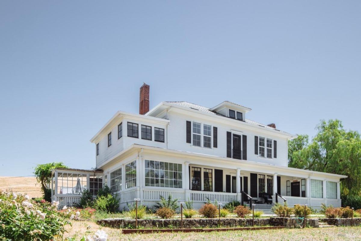 A large two-story white house with a porch and black shutters.