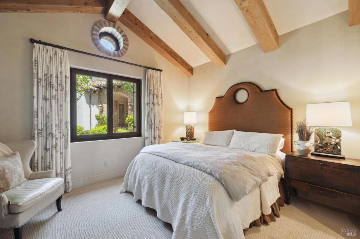 A bedroom with a bed featuring a woven headboard, decorative pillows, and a stylish nightstand.