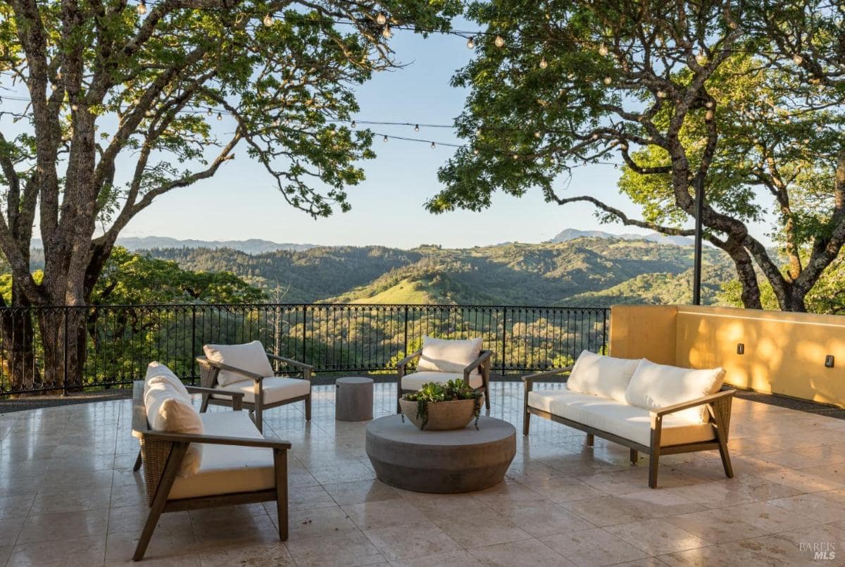 A terrace with outdoor seating overlooking a valley and hills.