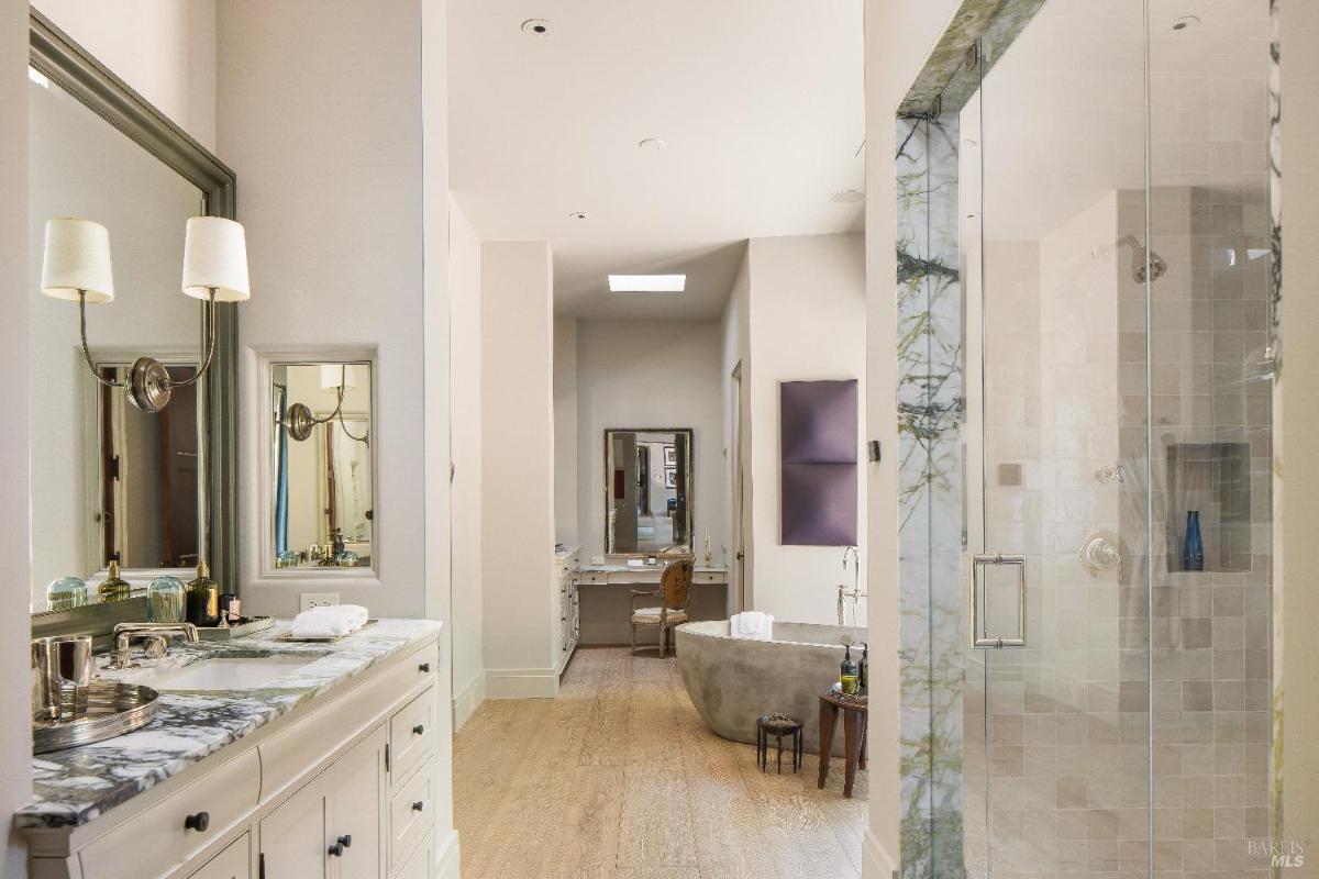 Bathroom with a double vanity, freestanding bathtub, and glass shower.