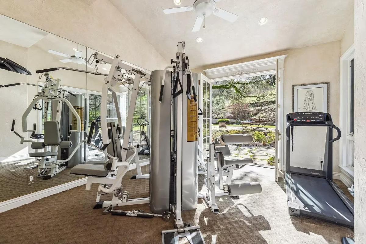 Home gym with fitness equipment, a mirrored wall, and access to an outdoor patio area.