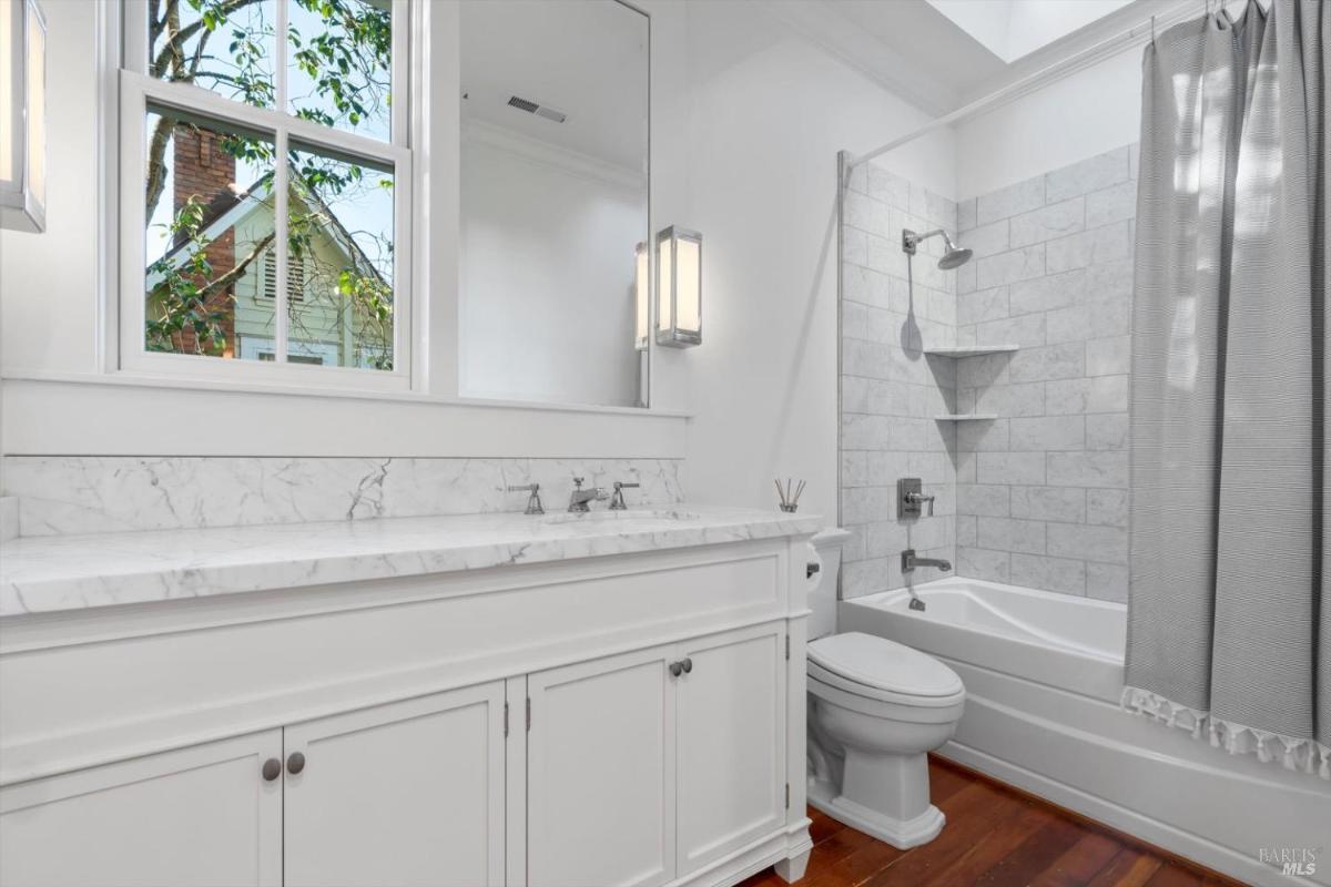 Bathroom with marble countertop, large mirror, and bathtub