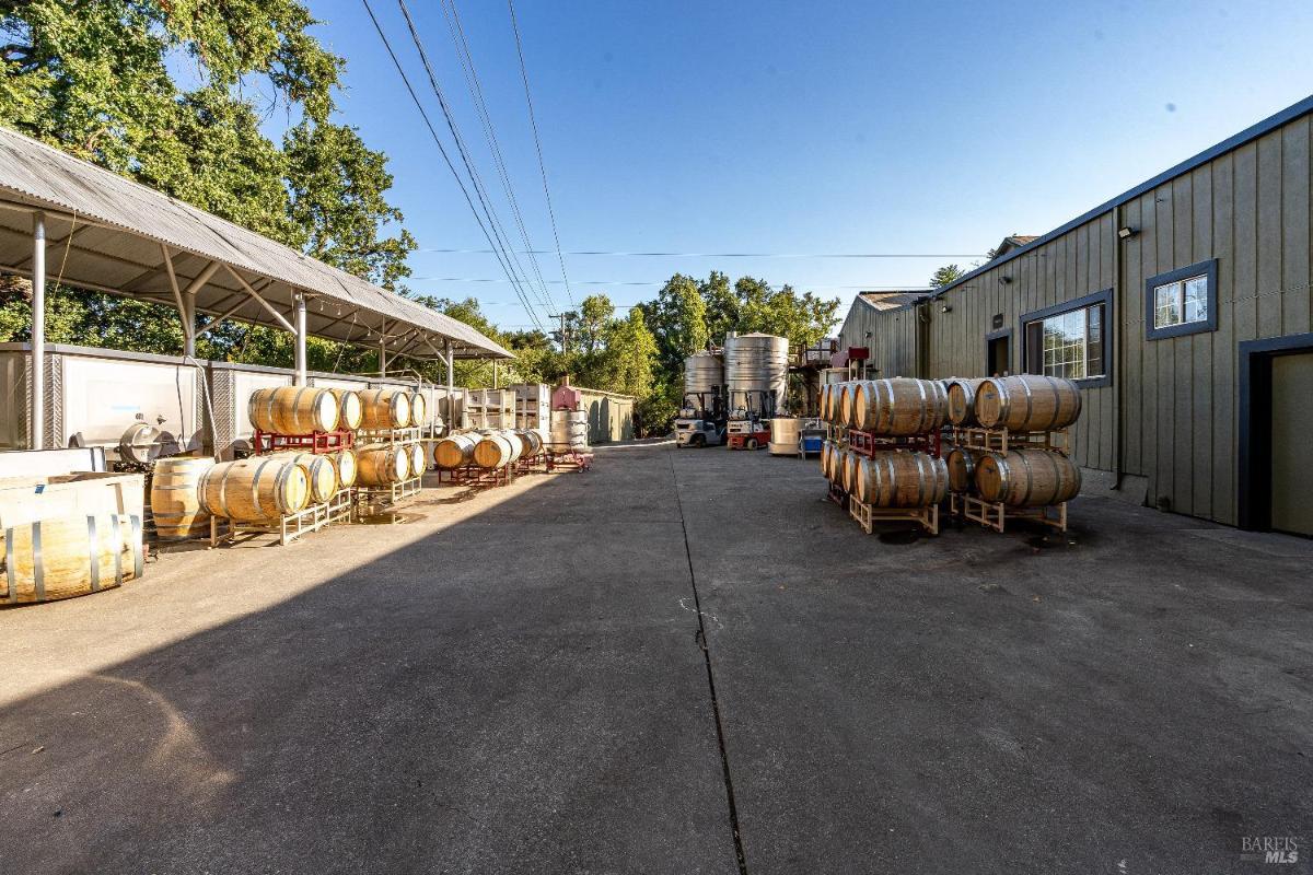 Outdoor area with wine barrels, tanks, and production facilities.