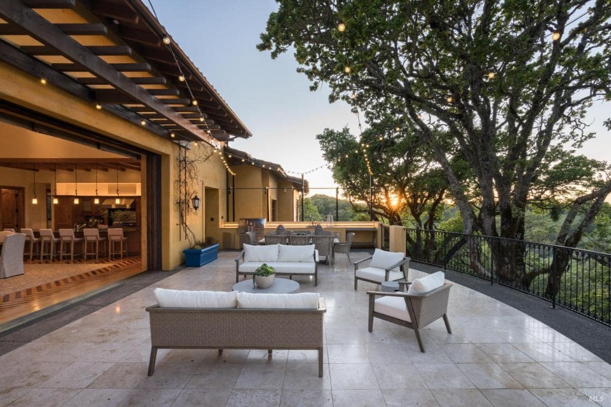 A terrace with seating and a view of the kitchen area through large open doors.