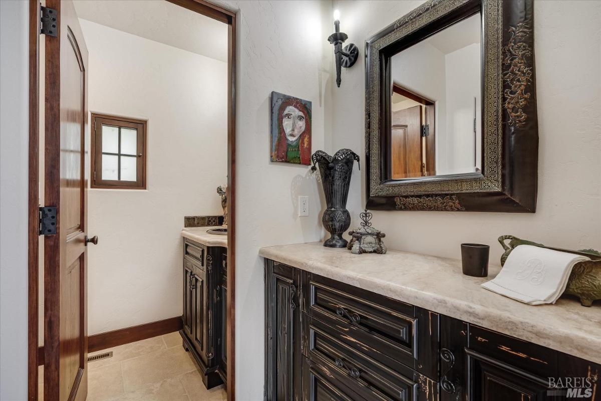 A half-bathroom with dark wood cabinetry, a mirror, and wall decor.