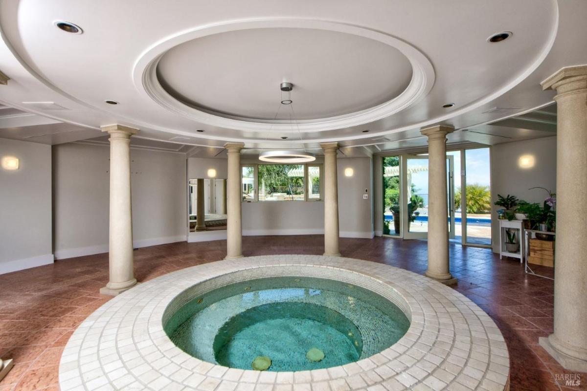 Indoor spa room with a circular hot tub and columns.