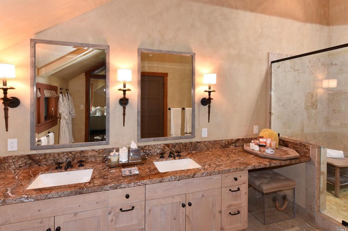 A bathroom featuring two sinks, a vanity desk, and wall-mounted mirrors.