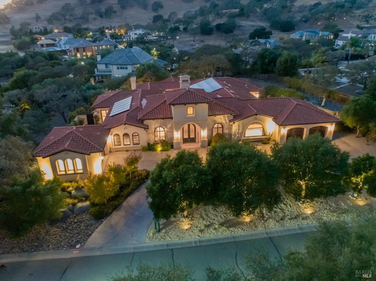 An aerial view of a large house with a tiled roof surrounded by trees and hills.