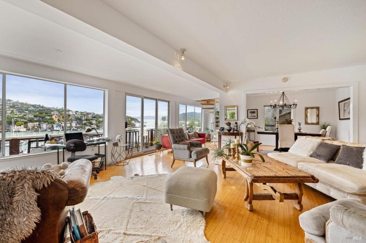 Open living room with seating, large windows, and views of the marina.