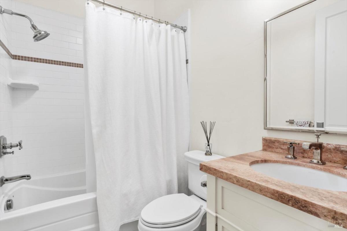 Compact bathroom with tub and curtain, featuring a single sink