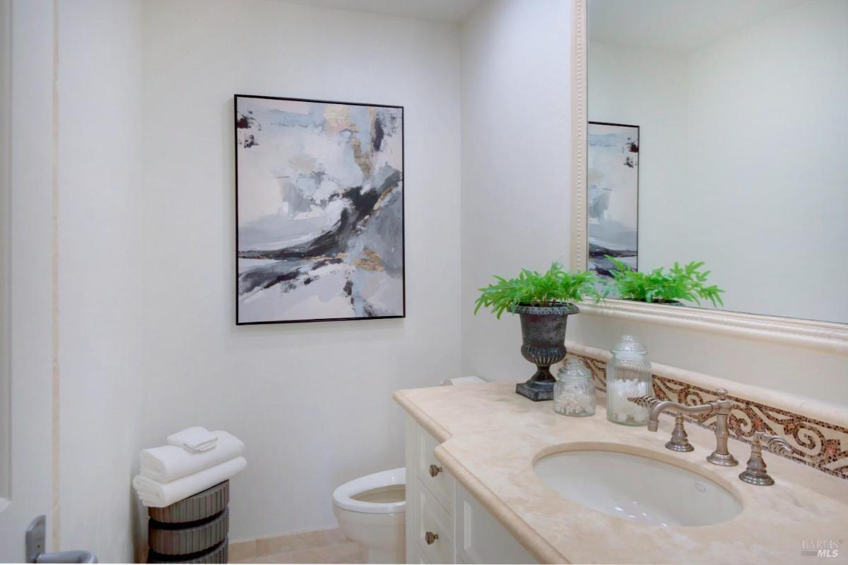 A bathroom with a single sink, beige countertop, and abstract wall art.