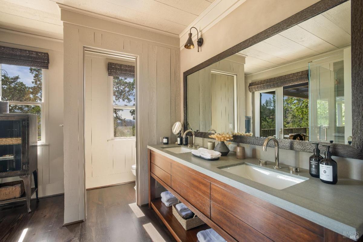 A modern bathroom with a wooden vanity and glass shower.