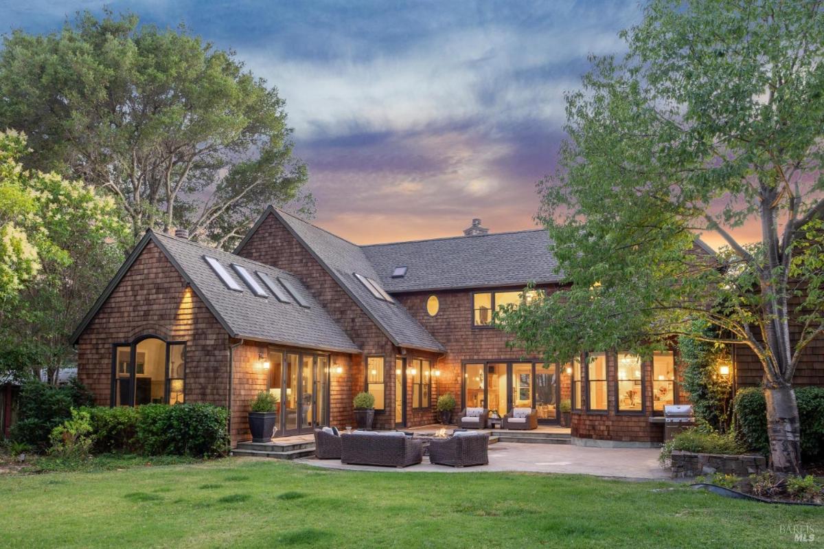 Rear exterior of a house with multiple windows and outdoor seating area. 