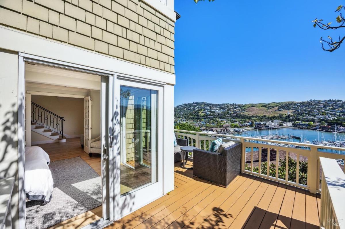 Outdoor deck with seating and views of a marina and hillside.