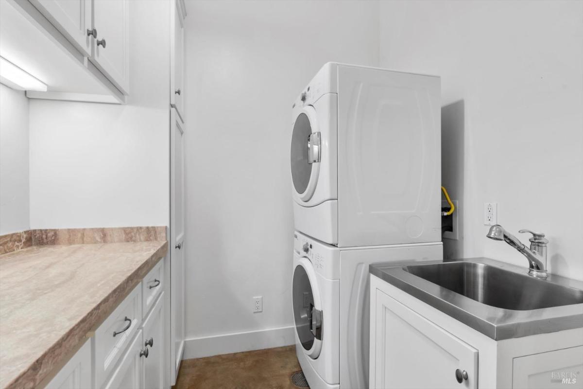 Laundry room with stacked washer and dryer, counter, and sink