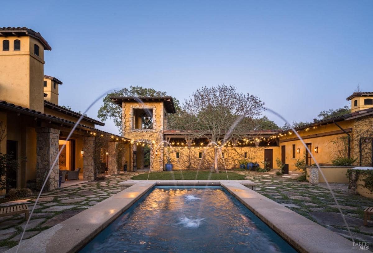 A courtyard with a rectangular fountain and surrounding buildings.