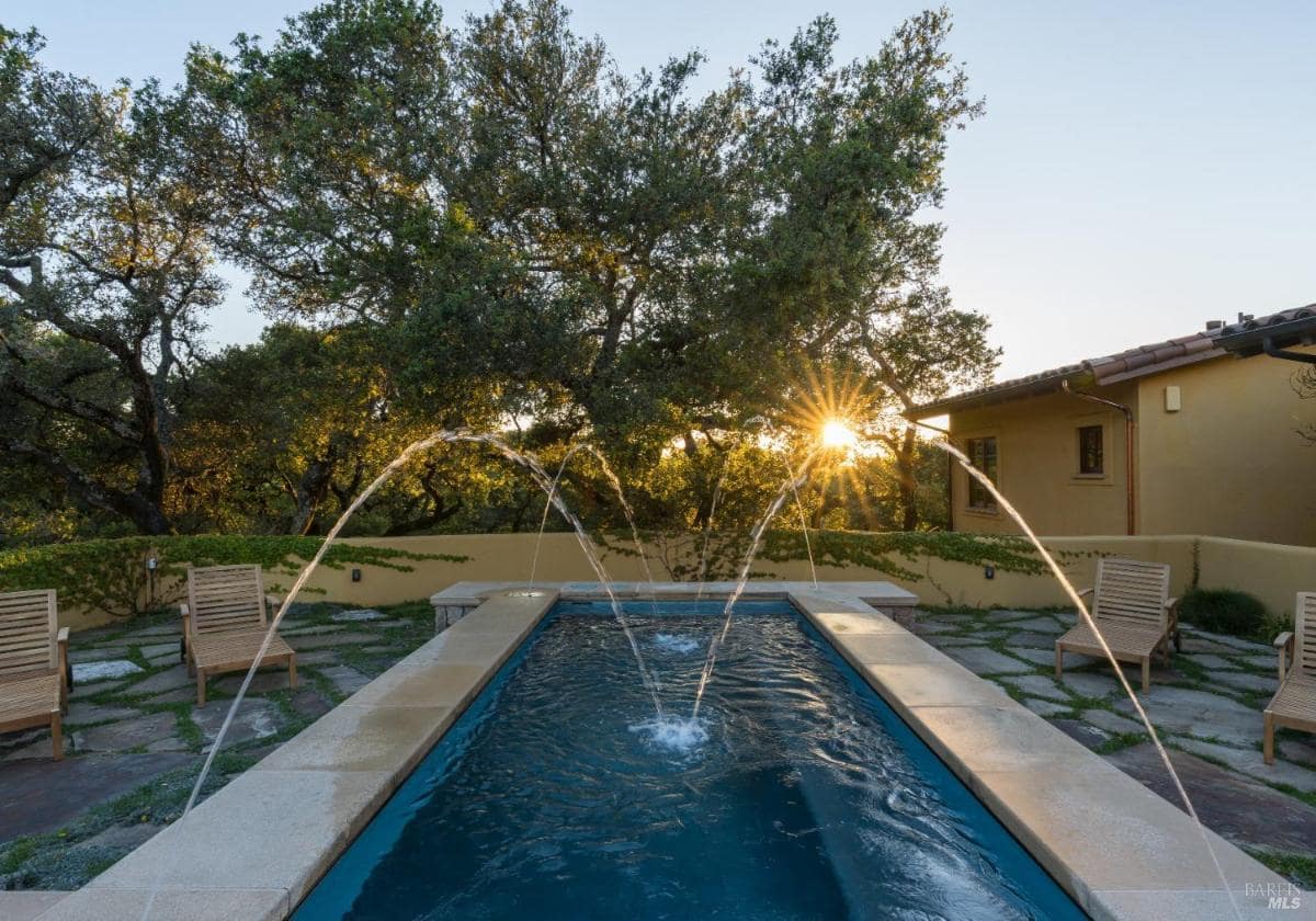 A pool with water features and trees in the background.